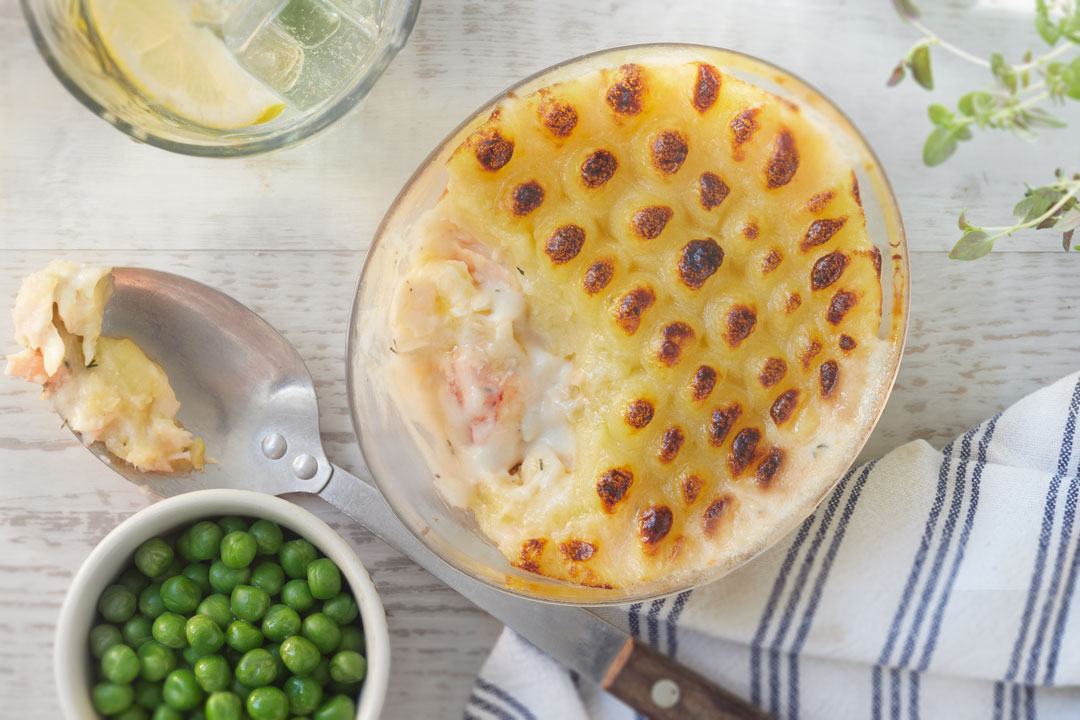 Image of Fish Pie with peas and some on a serving spoon.